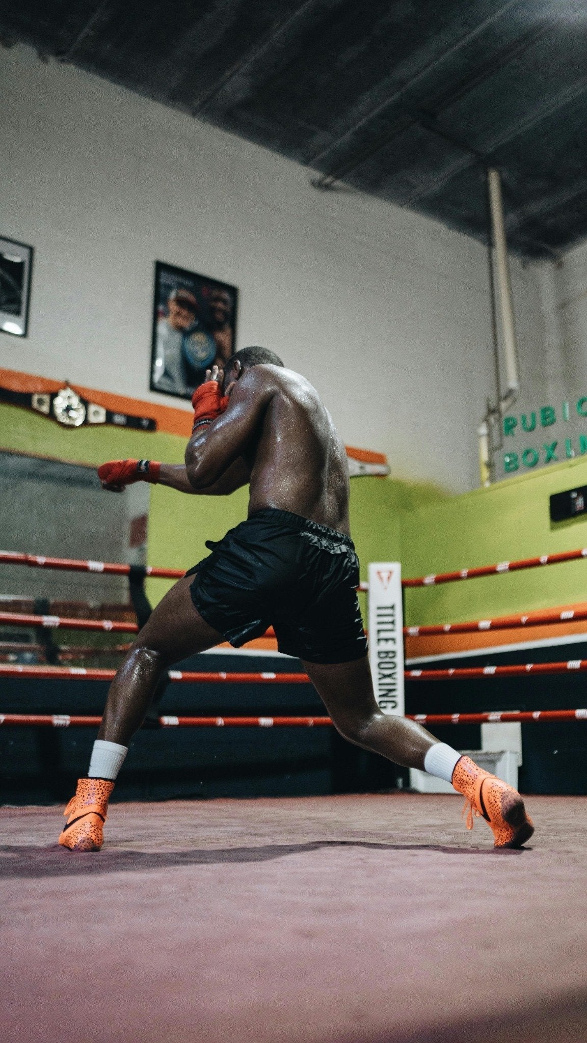 a boxer shadow boxes in the boxing ring with arma origin boxing brand gloves red handwraps 